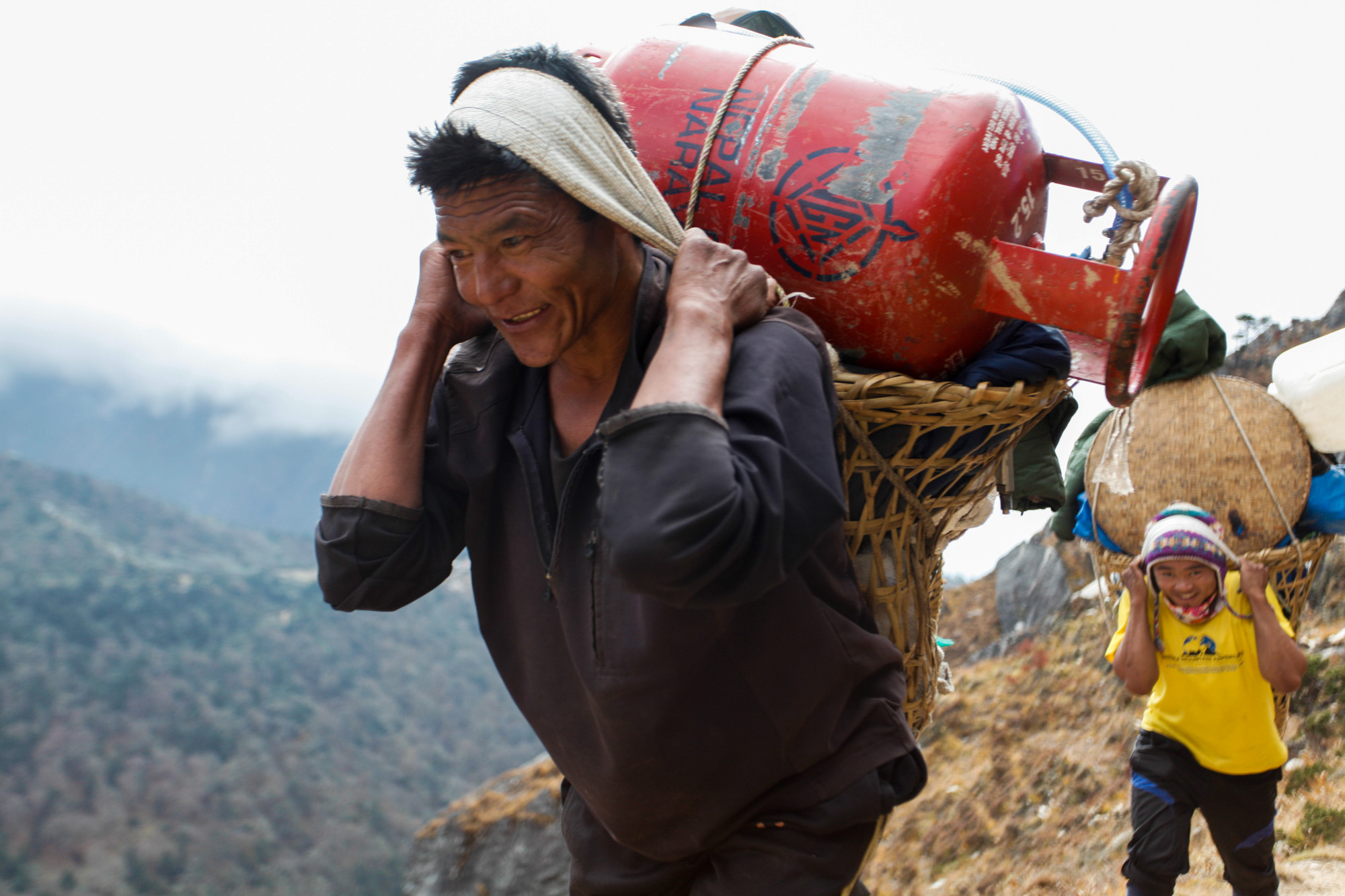 Sherpa smiling, while carrying a heavy load