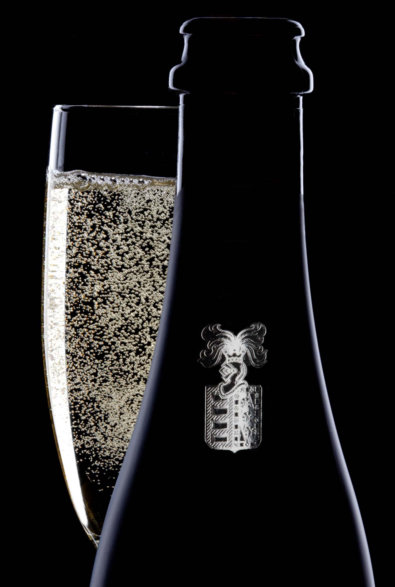 champagne bottle and glass on black. Dramatically lit product photography  