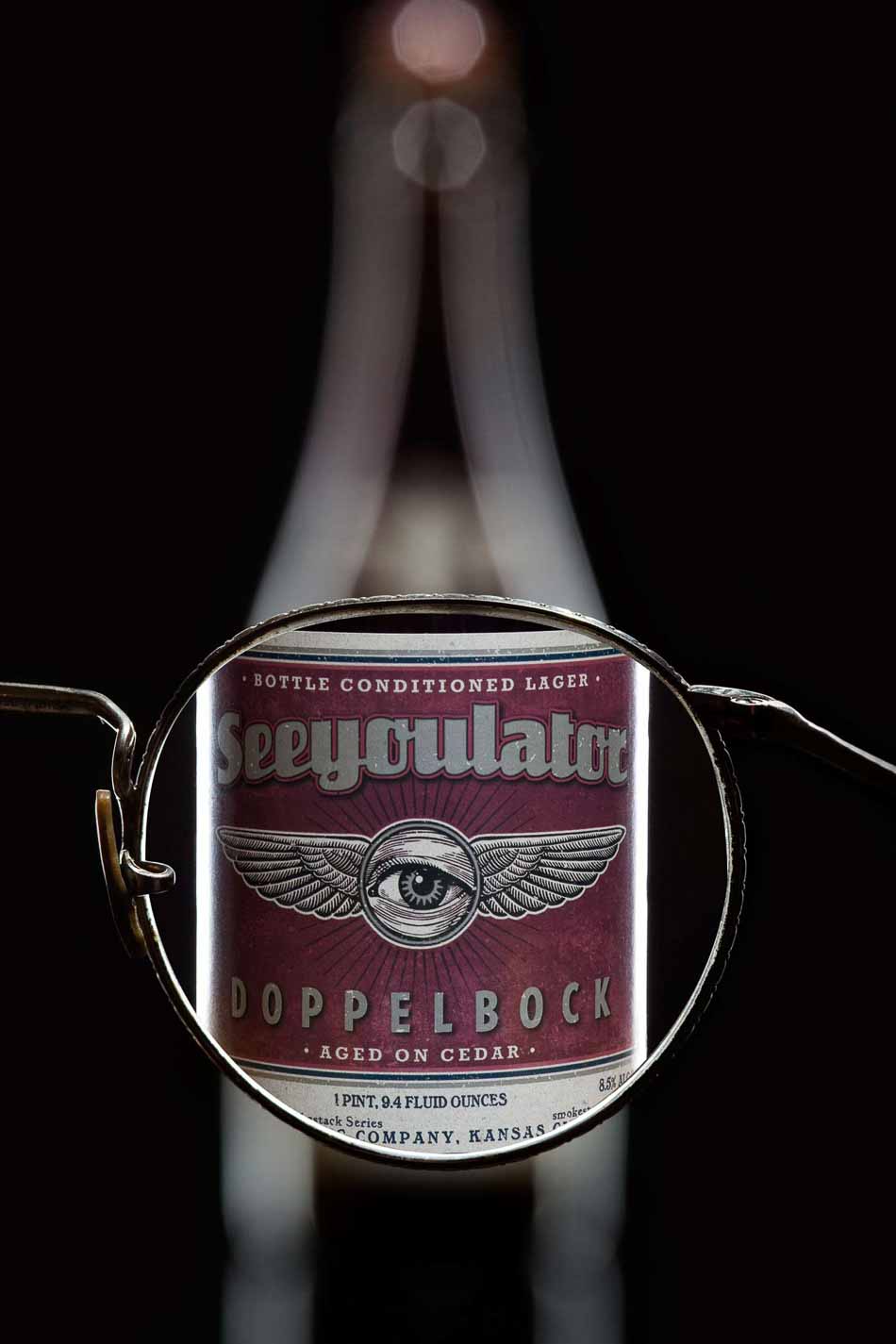 Looking through glasses lens making blurry beer bottle sharp - See You Later Doppelbock Cider | Bottle Photography | Dramatic Product Photography  | Still Life Photography | Shot in Denver, Colorado