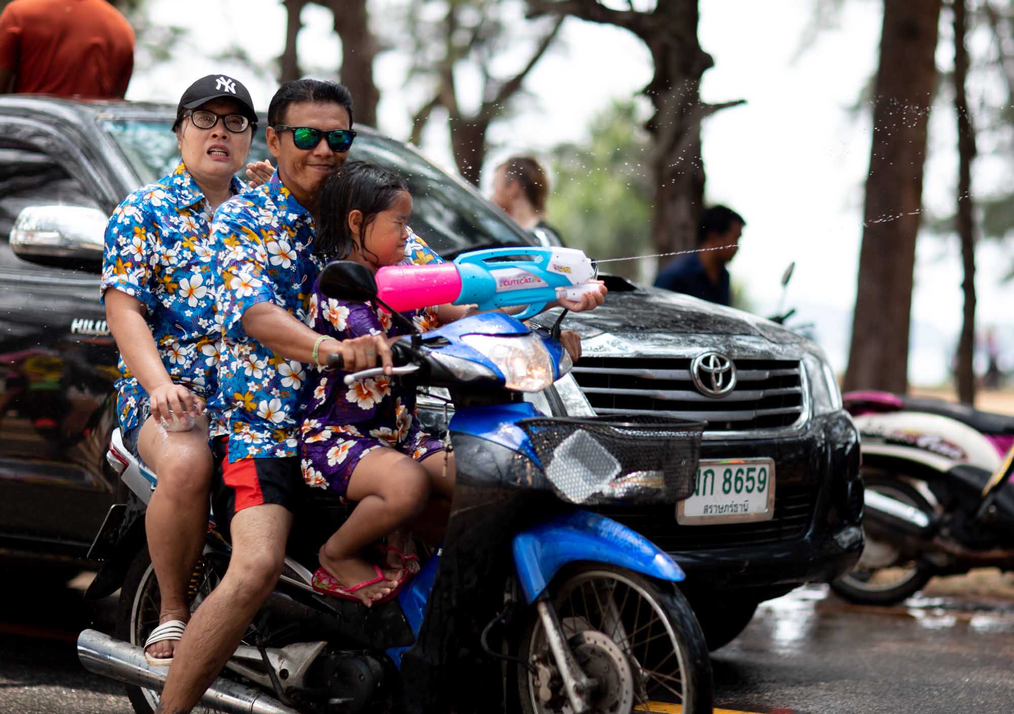Little girl shoots squirt gun on motorbike during Songkran water festival in Phuket, Thailand