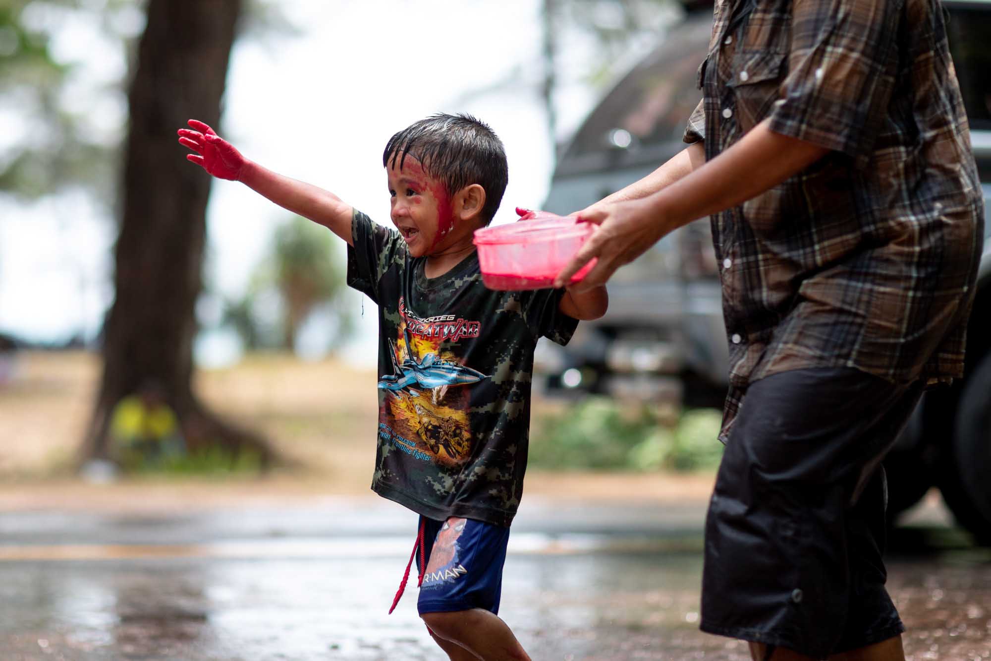 Happy young child coverd in paint celebrates Songkran water festival in Phuket, Thailand