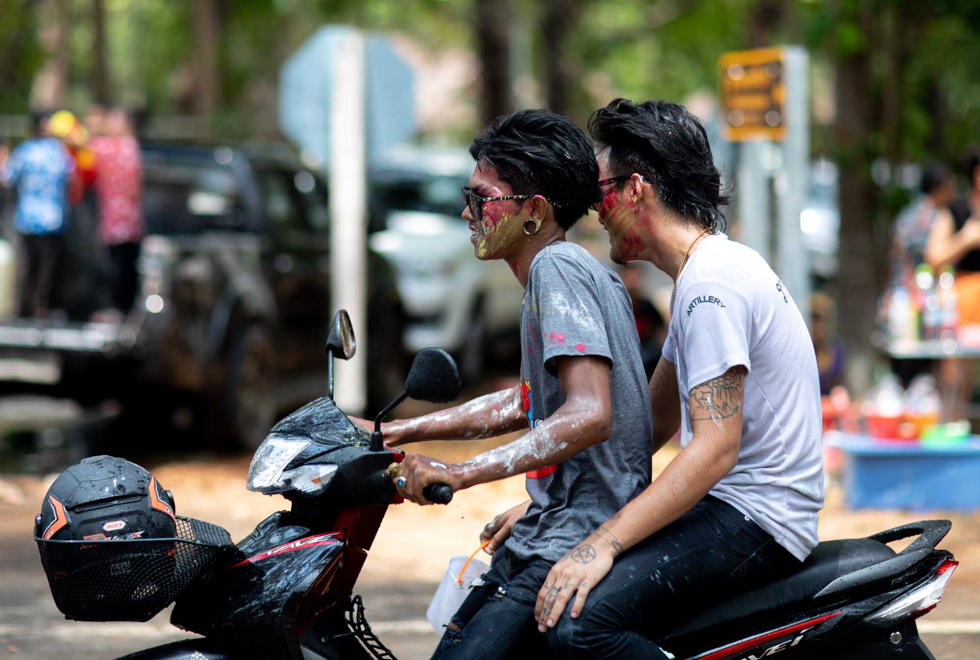 Two young men on a motorbike with paint on their faces at Songkran water festival in Phuket, Thailand