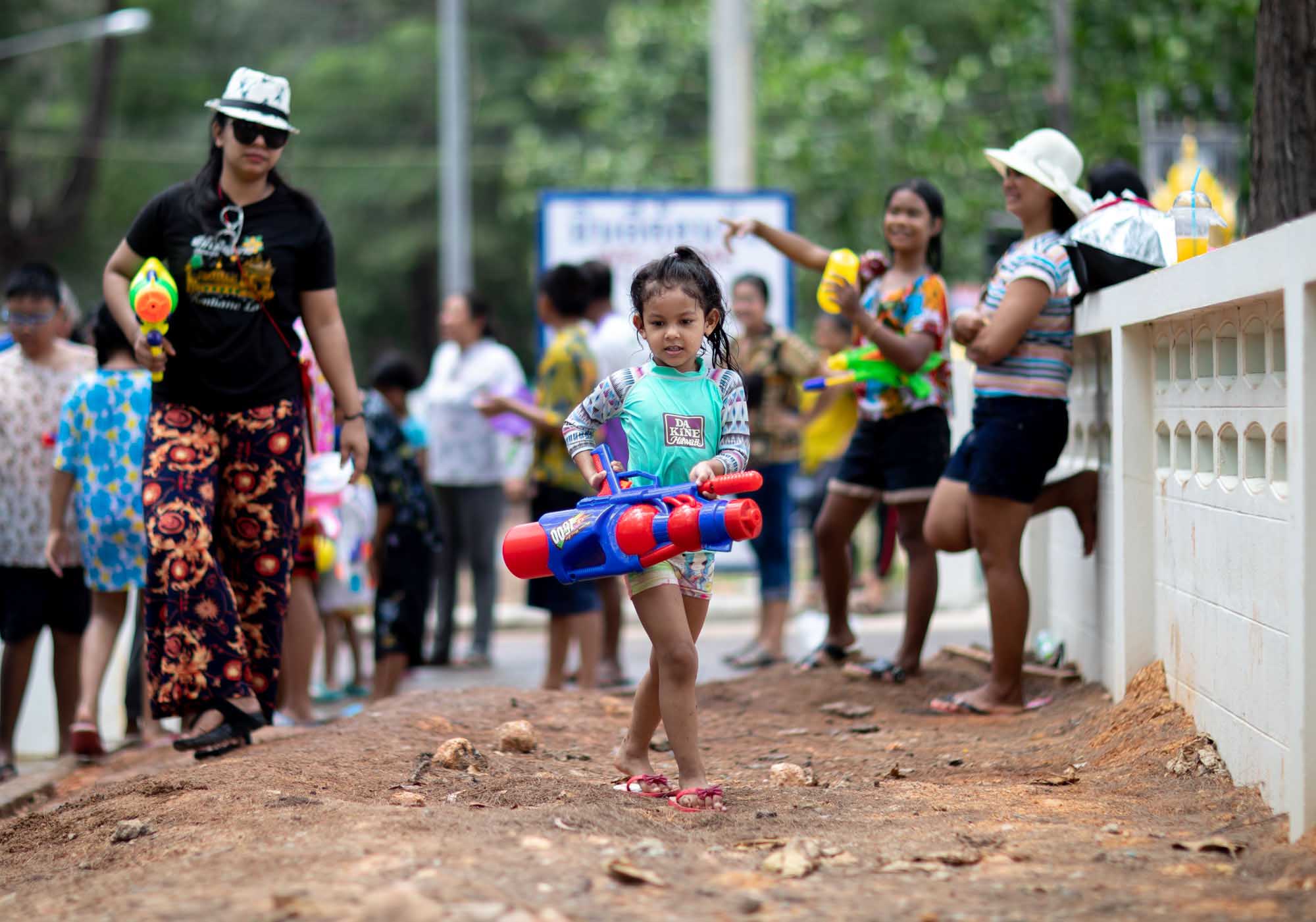 Young girl carries a big squirt gun during Songkran water festival in Phuket, Thailand