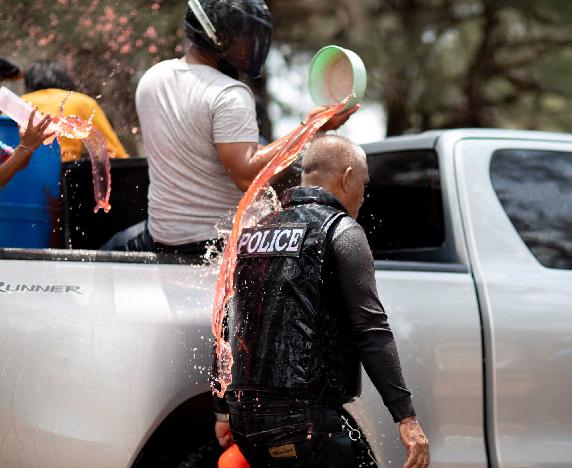 Thai man dumping water on a police officer - Songkran water festival in Phuket, Thailand