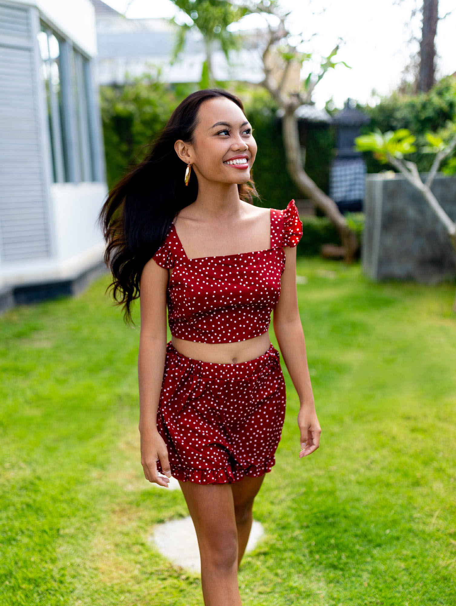 Woman walks in garden of luxury villa in Bali wearing red | Lifestyle Photography | Swimwear Photography | Asian Bali Model | High Key Photography | Fashion Photography