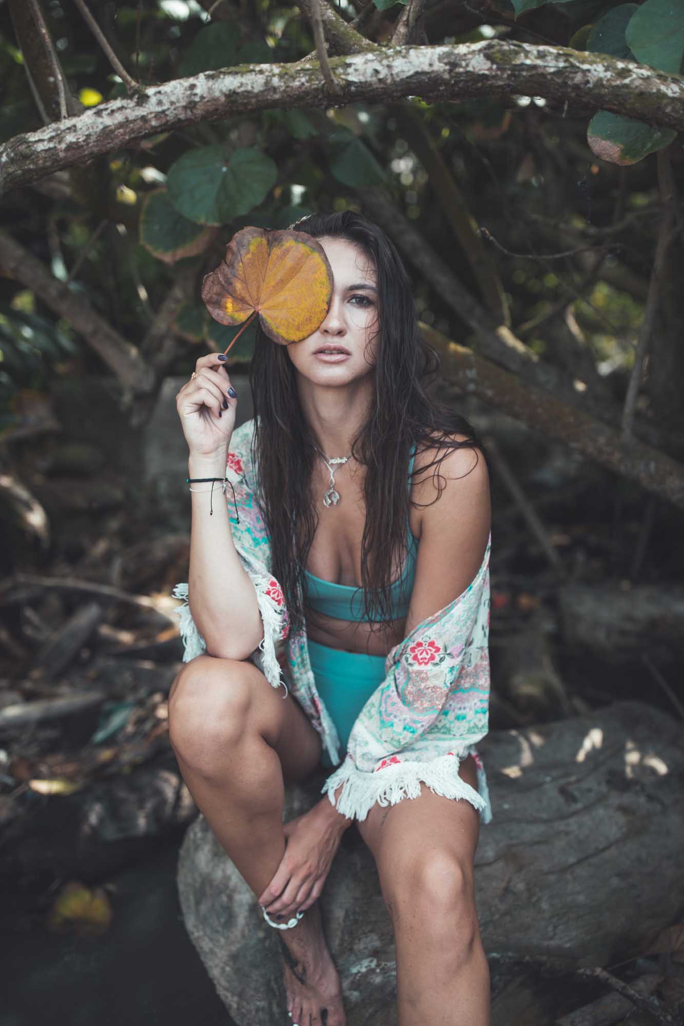 Beautiful woman in swimwear and cover-up holds a big yellow leaf in front of one of her eyes | Fashion Photography | Portrait | Lifestyle Photography | Pantai Mangening,Bali, Indonesia | Swimwear  Denver Photographer |