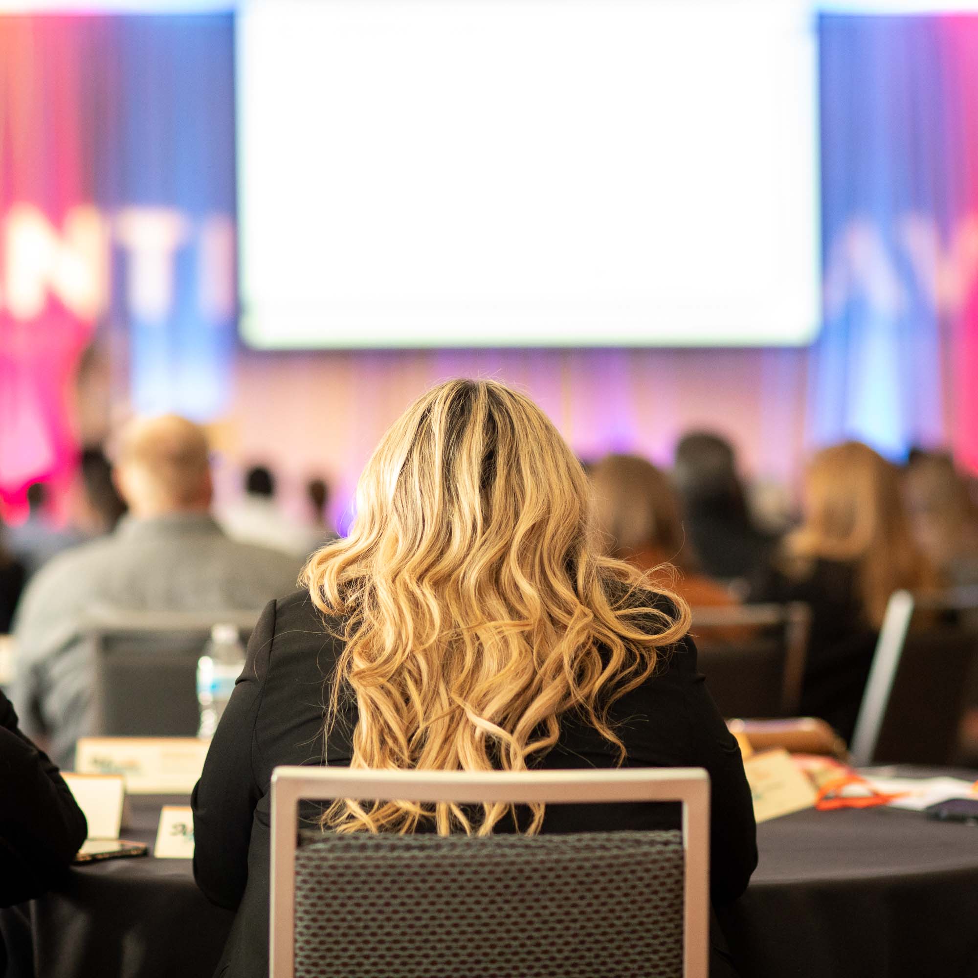A woman looks at the stage during a corporate conference