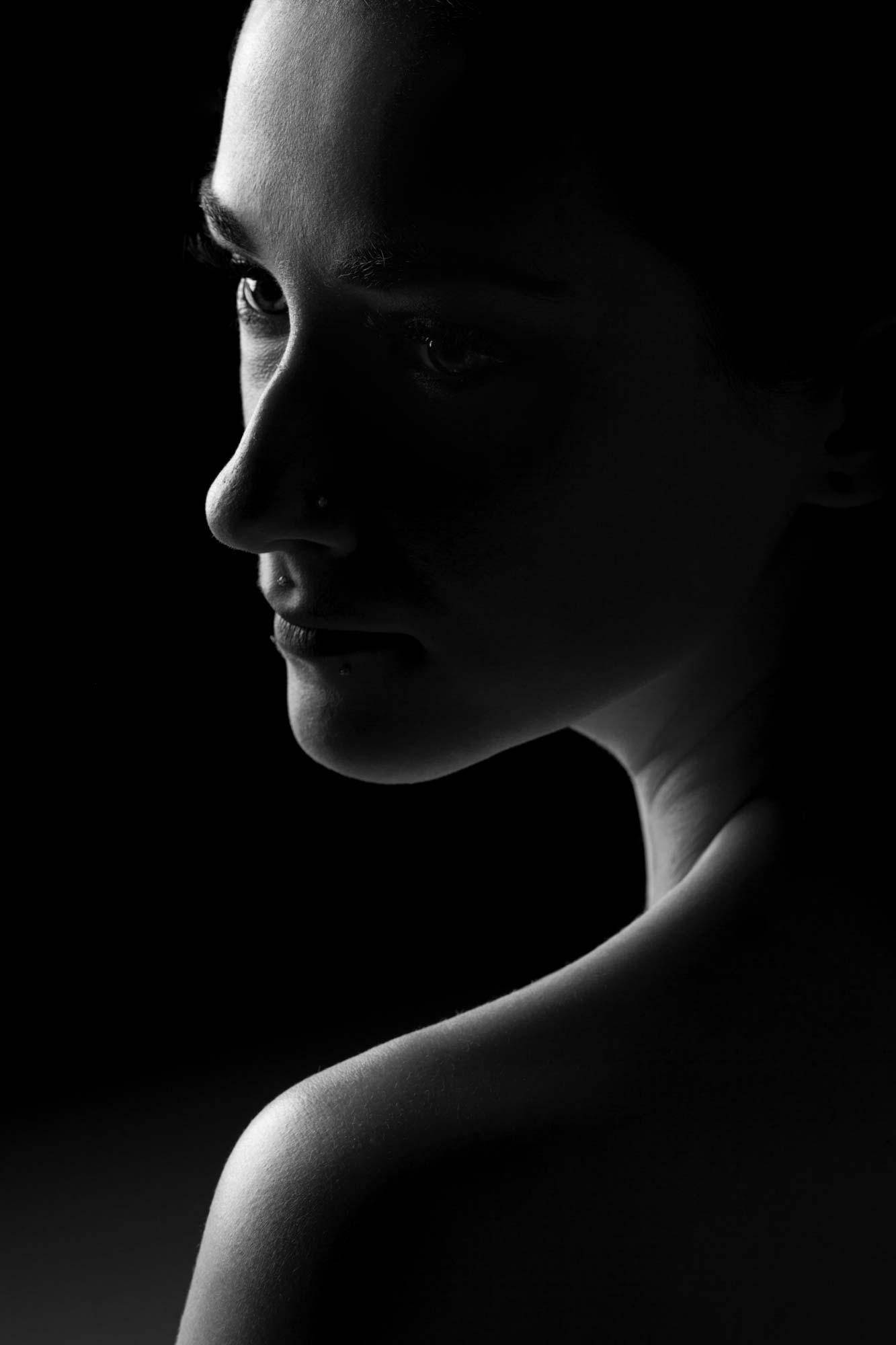 Black and white profile portrait of a woman in dramatic studio lighting.