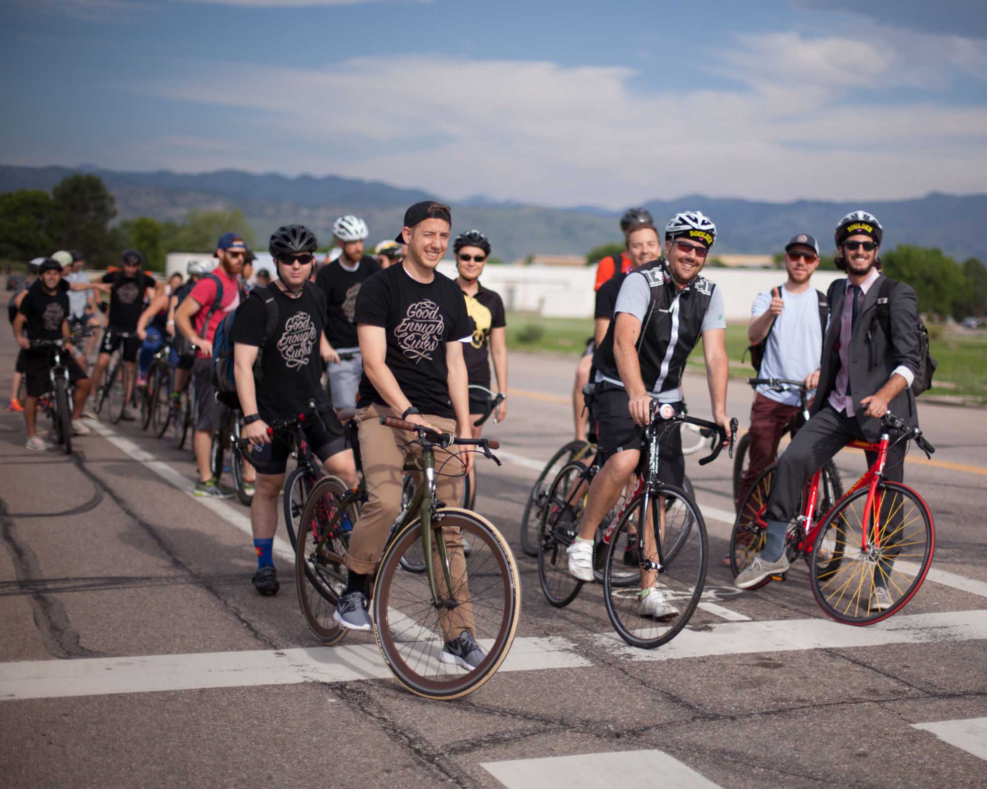 A CP+B Bike-to-Work Day group ride on an open road outside Boulder, Colorado, with the Flatirons foothills on the horizon.