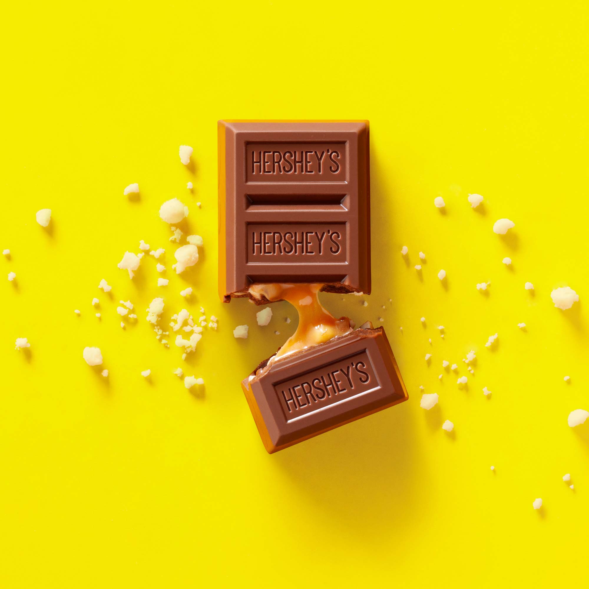 Studio product photography of a Hershey’s chocolate bar with caramel on a bright yellow background.