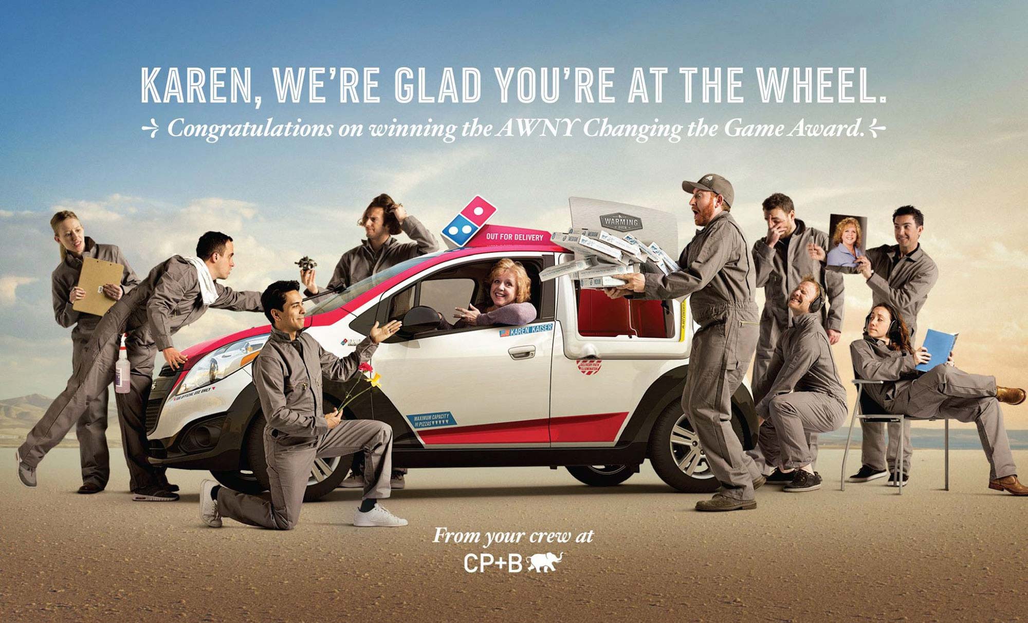 Composite group portrait of the CP+B creative team surrounding Domino's executive Karen Kaiser in a Domino's delivery car, celebrating her AWNY "Changing the Game" award.