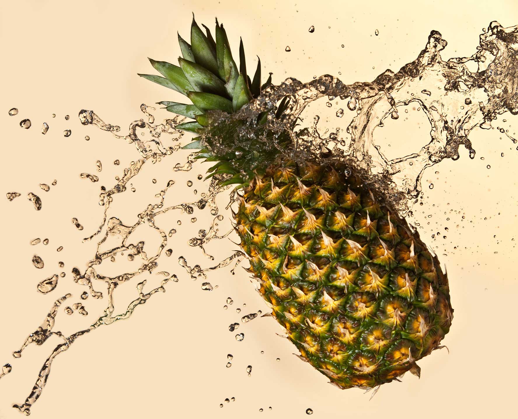 Studio product shot of a pineapple splashing through water