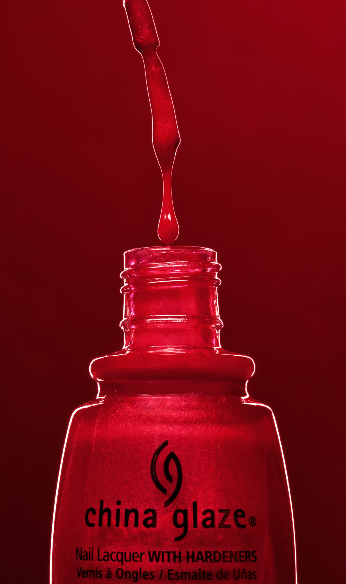 Product photography of a China Glaze red nail polish bottle with lacquer dripping from the brush