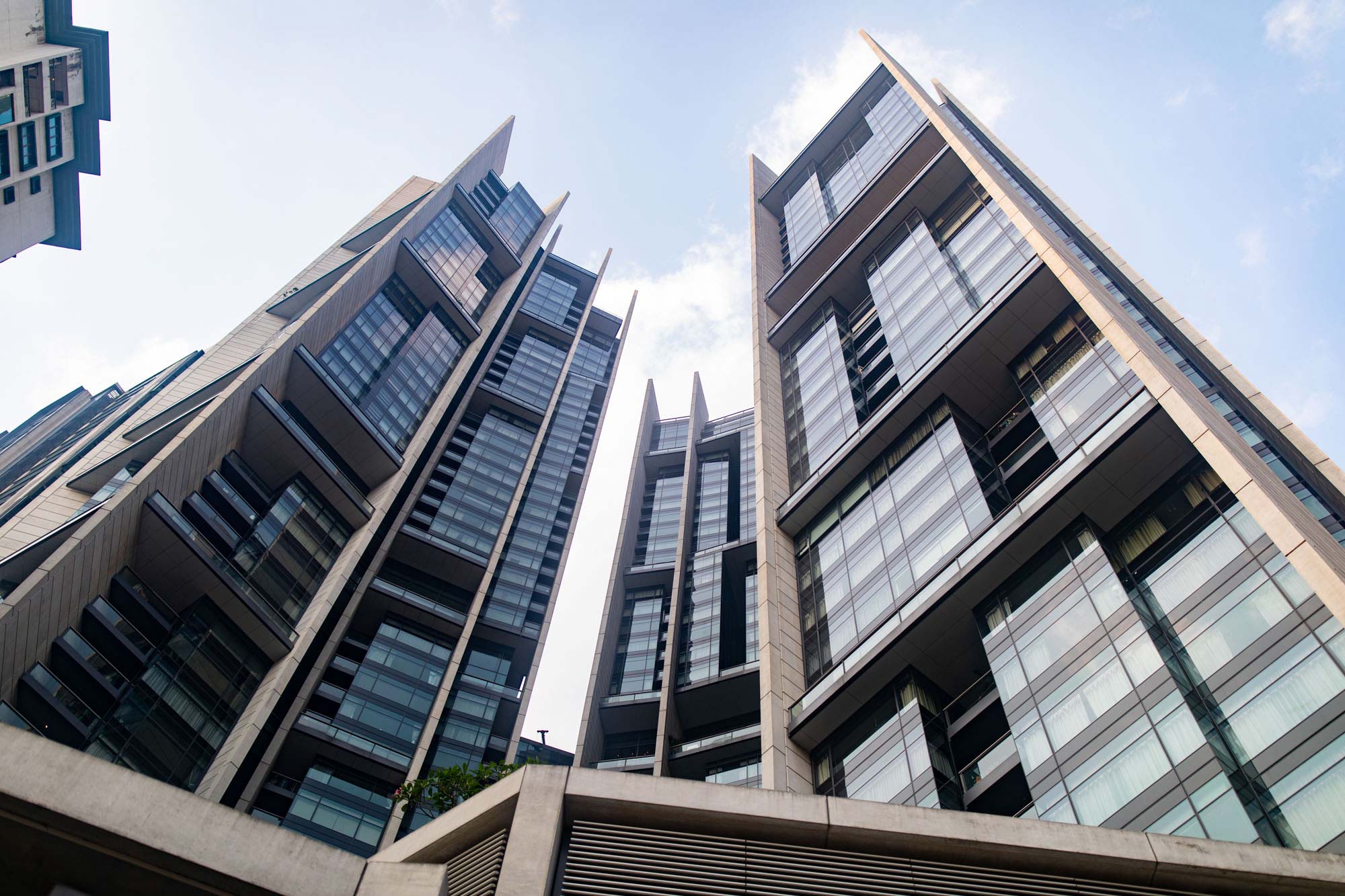 Low-angle architectural photograph of sharp-edged high-rise towers reaching into a blue sky in Kuala Lumpur, Malaysia.