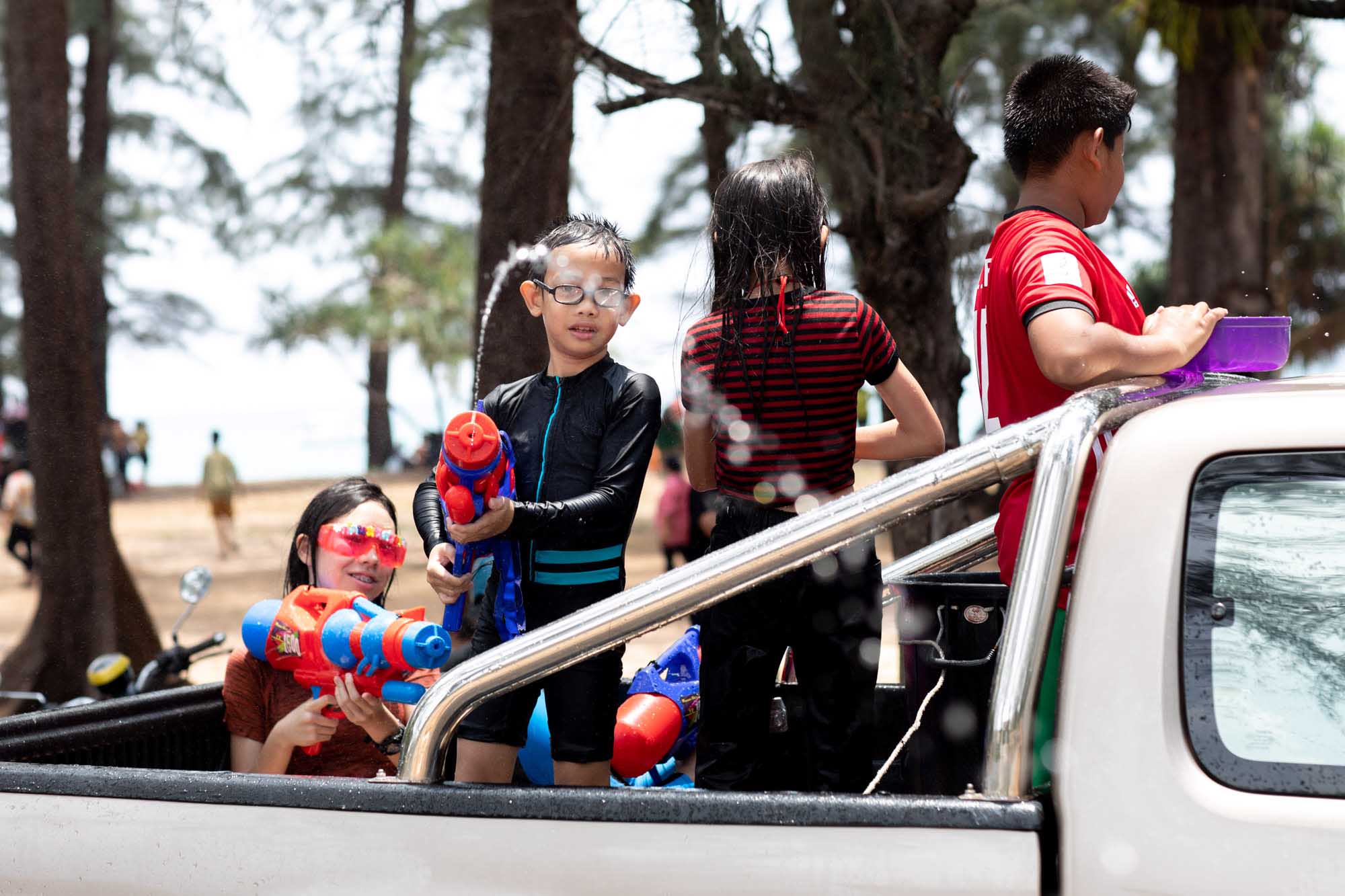 A boy in a Spider-Man rashguard and clear goggles aims a red water gun over the side of a pickup bed during the Songkran water festival in Phuket, Thailand.