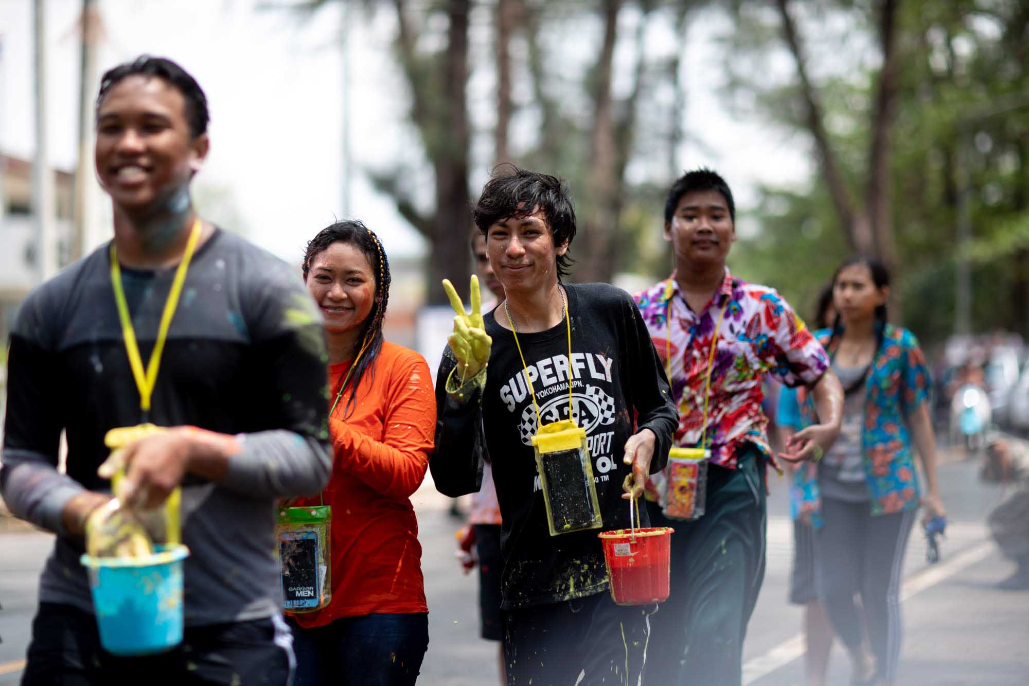 Young man flashes peace sign with paint covered hand at Songkran water festival in Phuket, Thailand