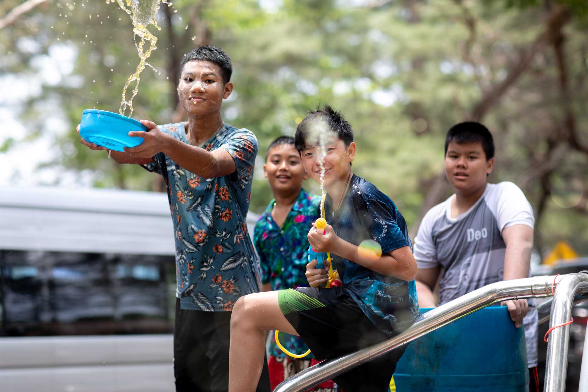 A teenage boy hurls water from a blue bucket over his friends perched on a pickup truck during the Songkran water festival in Phuket, Thailand.