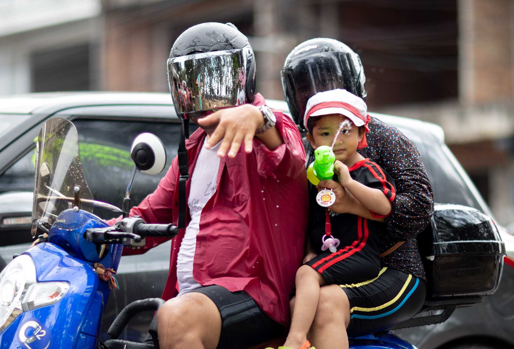 Little boy squirts water at camera during Songkran water festival in Phuket, Thailand