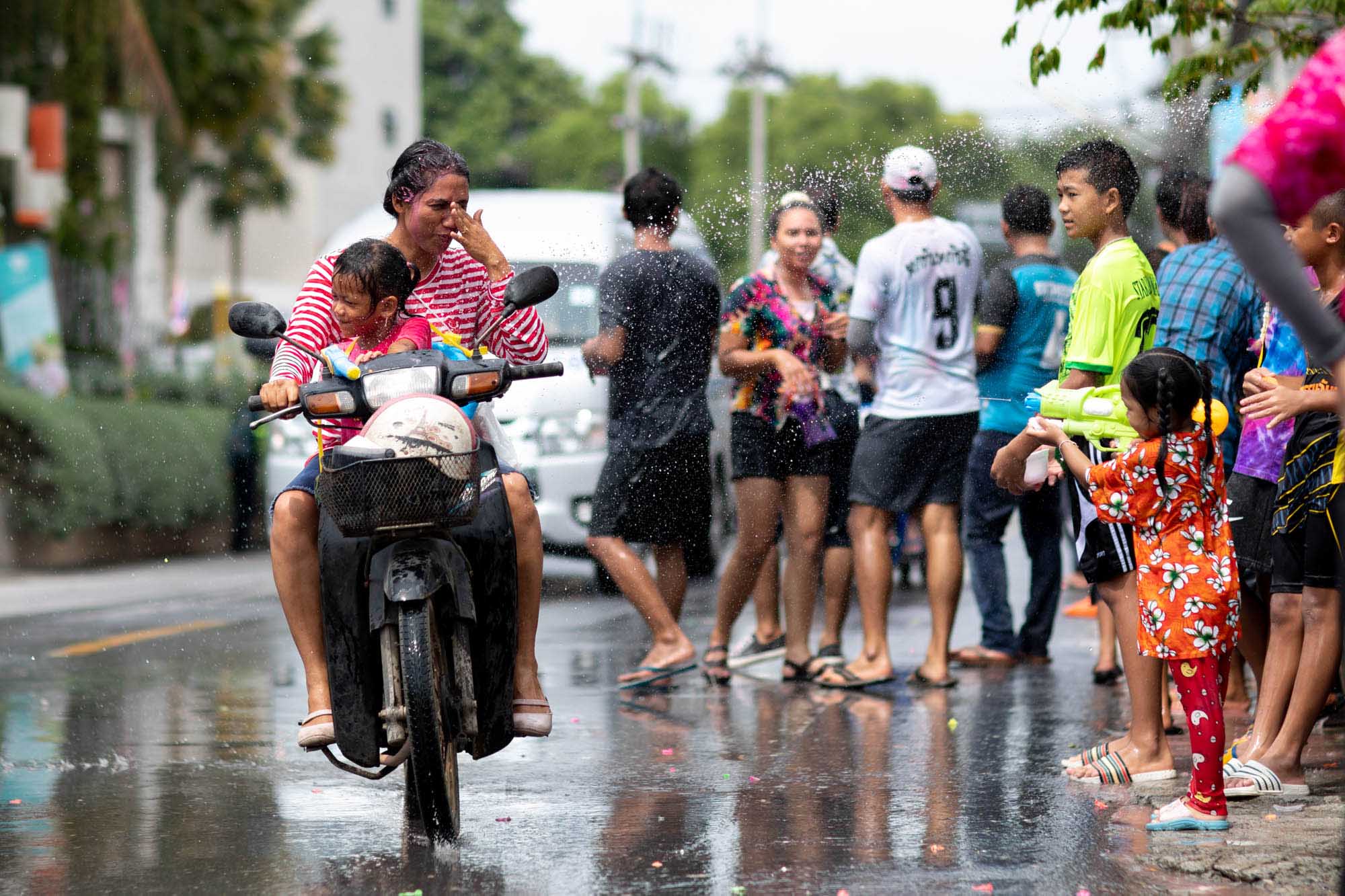 Woman wipes water from eyes at Songkran water festival in Phuket, Thailand