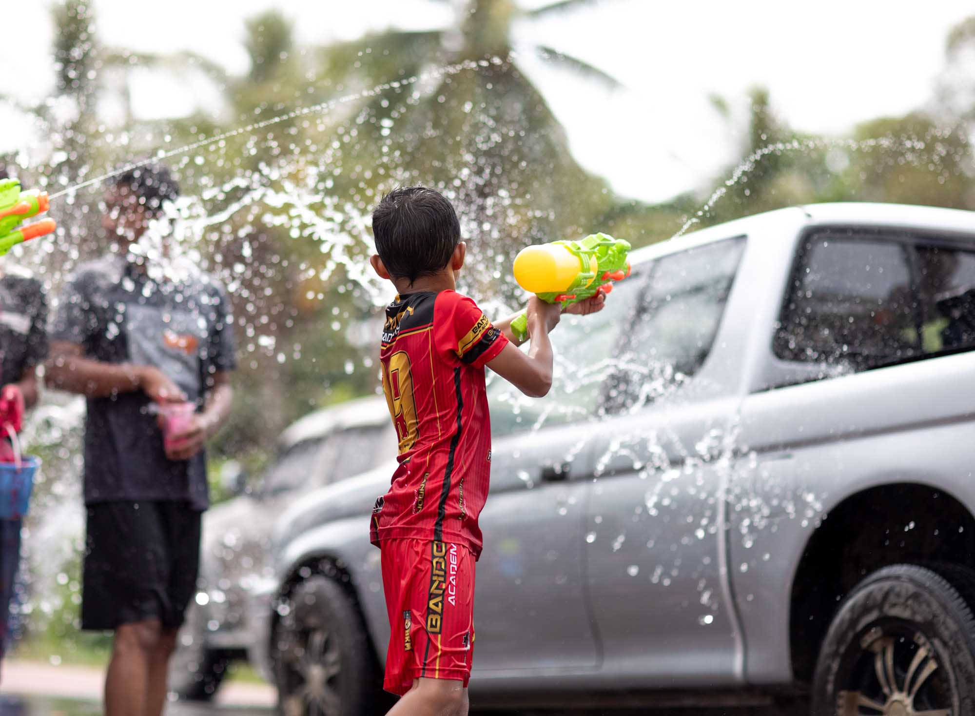 A boy in a red soccer jersey fires a yellow water gun during the Songkran water festival in Phuket, Thailand.